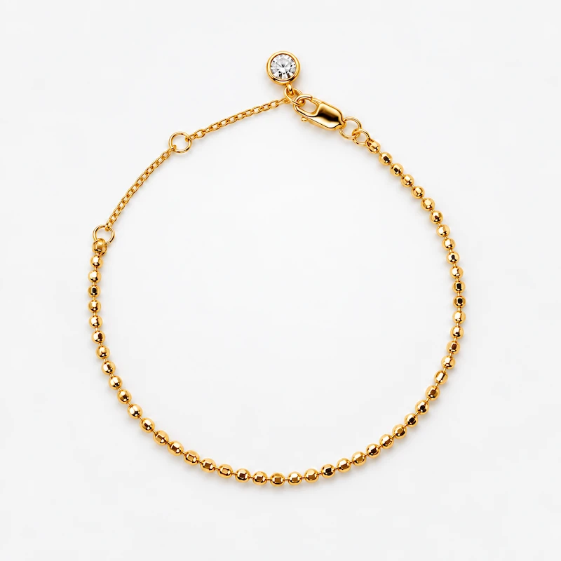 ONDA LENTA 18K gold plated sterling silver beaded bracelet with a clear stone charm and adjustable extension chain.