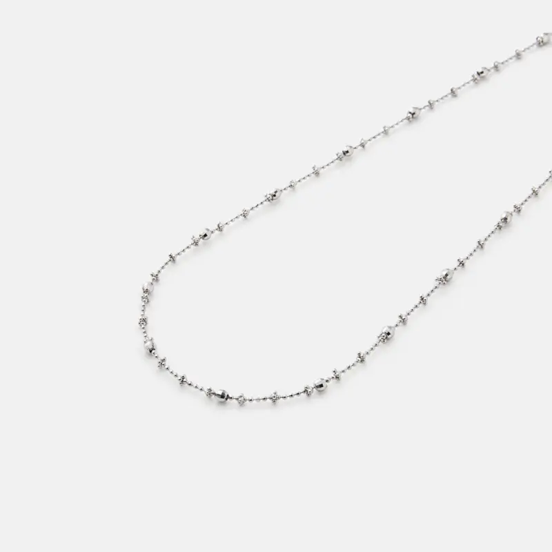 Detailed close-up view of the fine textured links and subtle reflective details on the strand of the chain necklace crafted with premium rhodium plating