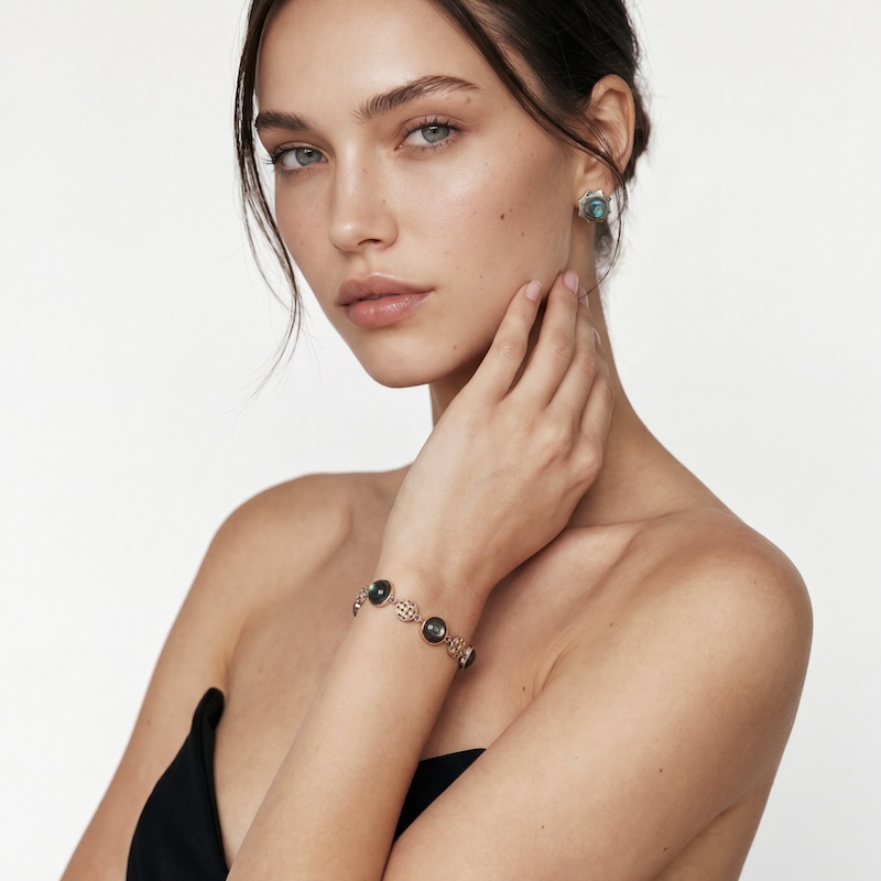 A close-up shot of a female model wearing the iridescent Star Abalone Shell Stud Earrings on her earlobe, paired with a matching multi-stone bracelet on her wrist for a sophisticated look.