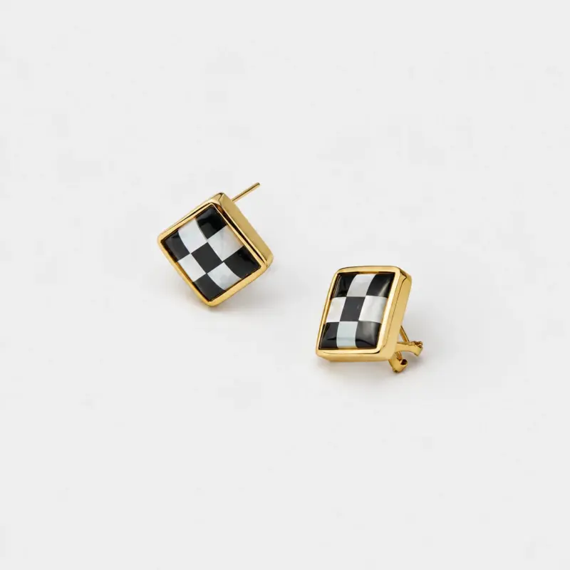 Angled detail view showing the checkerboard inlay of black agate and mother of pearl square stud earrings with an 18K gold plated frame.
