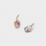 Angled detail view showing the iridescent pink and lavender glow of the natural flat baroque pearl studs with a sparkling prong-set stone accents.