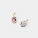 Angled detail view showing the iridescent pink and lavender glow of the natural flat baroque pearl studs with a sparkling prong-set stone accents.