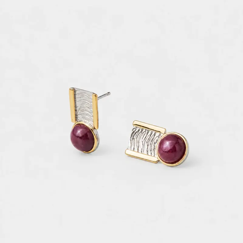 Angled detail view showing the rippled textured silver surface of the geometric stud earrings with a gold plated frame backing.