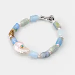 Angled view of an ONDA LENTA beaded bracelet featuring blue-green gemstones, freshwater pearls, a baroque pearl centerpiece and silver-tone clasp.