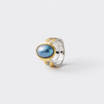 Close-up detailed view showcasing the ocean-like glow of the blue mabe pearl and the intricate mixed-metal ridges of the statement ring band crafted with 18K gold plating and sterling silver
