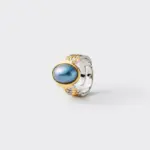 Close-up detailed view showcasing the ocean-like glow of the blue mabe pearl and the intricate mixed-metal ridges of the statement ring band crafted with 18K gold plating and sterling silver