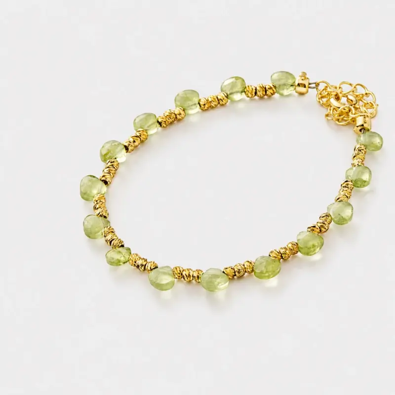 Close-up detailed view highlighting the smooth light green peridot beads and textured gold-tone spacers on this beaded strand bracelet crafted with 18K gold plated sterling silver