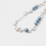 Close-up detail view showcasing the hazy matte texture and misty cloud inclusions of round blue chalcedony beads layered with organic petal-shaped baroque pearls on a sterling silver wire
