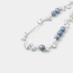 Close-up detail view showcasing the hazy matte texture and misty cloud inclusions of round blue chalcedony beads layered with organic petal-shaped baroque pearls on a sterling silver wire