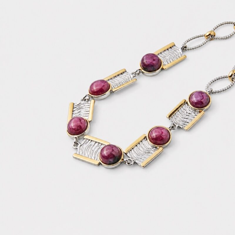 Close-up detail view showing the handcrafted wavy textures on the rectangular silver panels of the gemstone bracelet framed by polished gold borders.