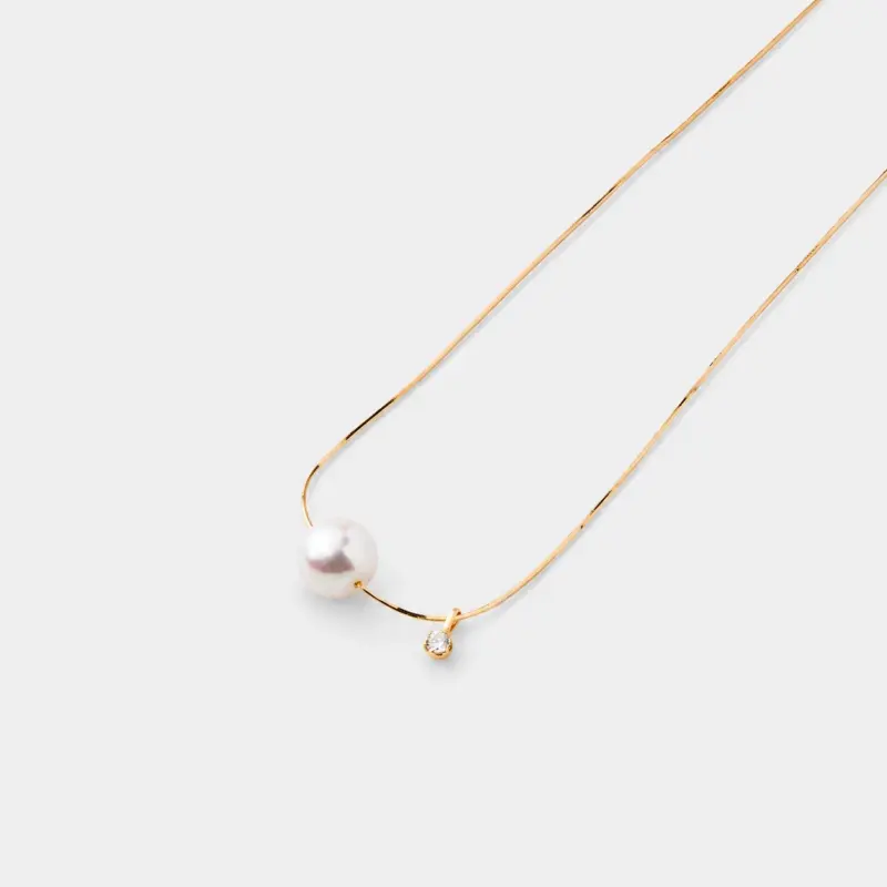 An elegant and polished 14K Gold Vermeil necklace with a singular, lustrous white pearl and a tiny sparkling cubic zirconia charm, perfect for achieving a refined, everyday look.