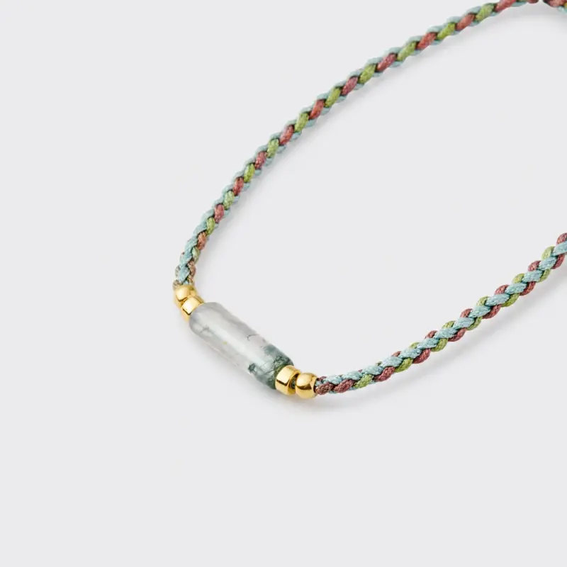 Close-up detailed view of the textured woven braided cord and smooth gradient green chalcedony beads on the focal strand bracelet with 18K gold plated sterling silver accents