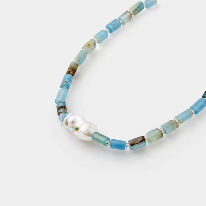 Close-up perspective view showing a baroque pearl with turquoise inlay and cylindrical blue opal beads on a 925 sterling silver necklace.