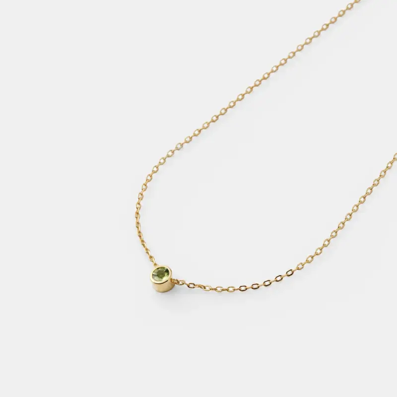 Detailed close-up view showcasing the round bezel-set green peridot stone on a fine 18K gold plated sterling silver cable chain