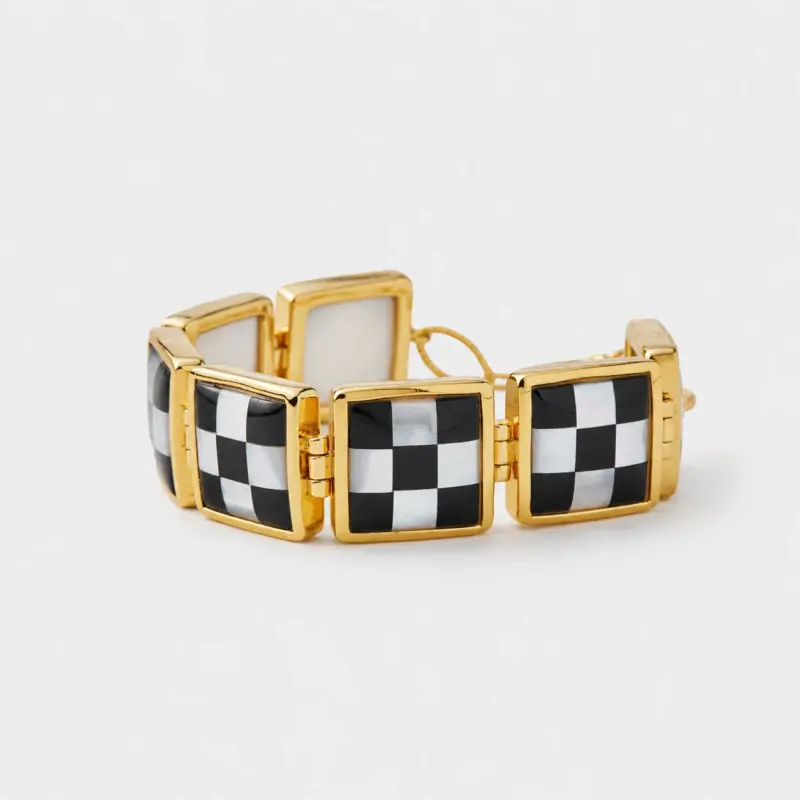 Close-up view showing the black and white checkerboard pattern on the square gemstone panels connected by gold plated sterling silver links.