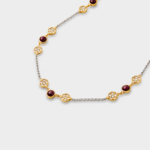 Close-up view showing the detailed cubic zirconia pavé blossom frames and smooth ruby beads on a two-tone silver and gold chain.