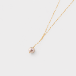 Close-up view showing a pink pearl charm and elongated links on a drop necklace with 14K gold-filled hardware.