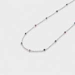 Close-up view showing the red, green, and blue corundum beads spaced along a fine link chain with rhodium plated silver finish.