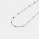 Close-up view showing the red, green, and blue corundum beads spaced along a fine link chain with rhodium plated silver finish.