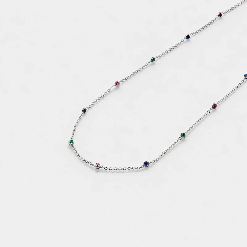 Close-up view showing the red, green, and blue corundum beads spaced along a fine link chain with rhodium plated silver finish.