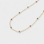 Close-up view showing red, green, and deep blue corundum accents spaced along a fine gold chain necklace in 18K gold plated silver.