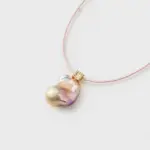 Close-up perspective view showing a square gold clasp and a baroque pearl pendant necklace with 14K gold-filled accents.