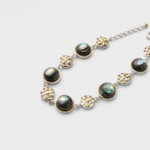 Close-up view showing the basket-weave metal patterns and iridescent round abalone shell panels of the link bracelet framed in gold plating.