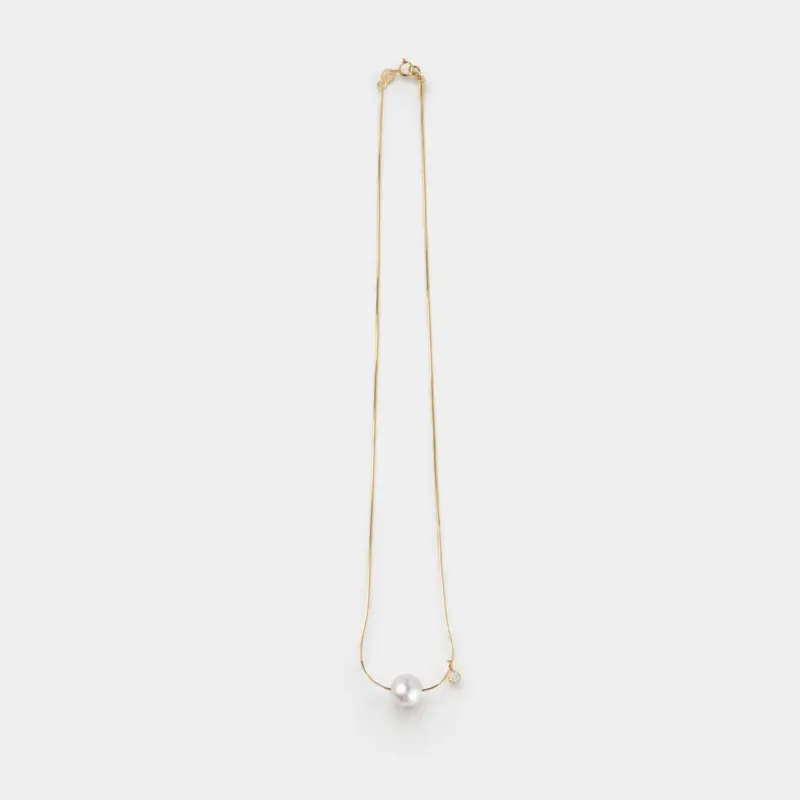 An elegant and polished 14K Gold Vermeil necklace with a singular, lustrous white pearl and a tiny sparkling cubic zirconia charm, perfect for achieving a refined, everyday look.