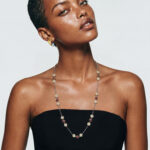 Model wearing Blossom Ruby Necklace draped elegantly over a black strapless top for a sophisticated everyday look.