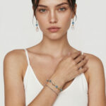 Model wearing the Swallowtail Fish Topaz Bracelet layered with a fine beaded bracelet around her wrist for a sophisticated coastal stacked look, demonstrating a distinctive jewelry style
