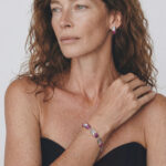 Model wearing Maya Ruby Stud Earrings on her earlobe paired with a matching natural gemstone bracelet for a modern workwear look.
