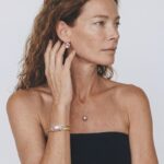 Model wearing Petal Baroque Pearl Stud Earrings on her earlobes paired with a matching natural pearl pendant necklace and gold cuff bracelet.