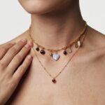 Model wearing Sweet Heart-Shaped Necklace layered beautifully with a charm choker at her neckline.