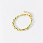 ONDA LENTA peridot bracelet featuring faceted light green peridot beads, gold-tone accent beads and an adjustable extension chain.