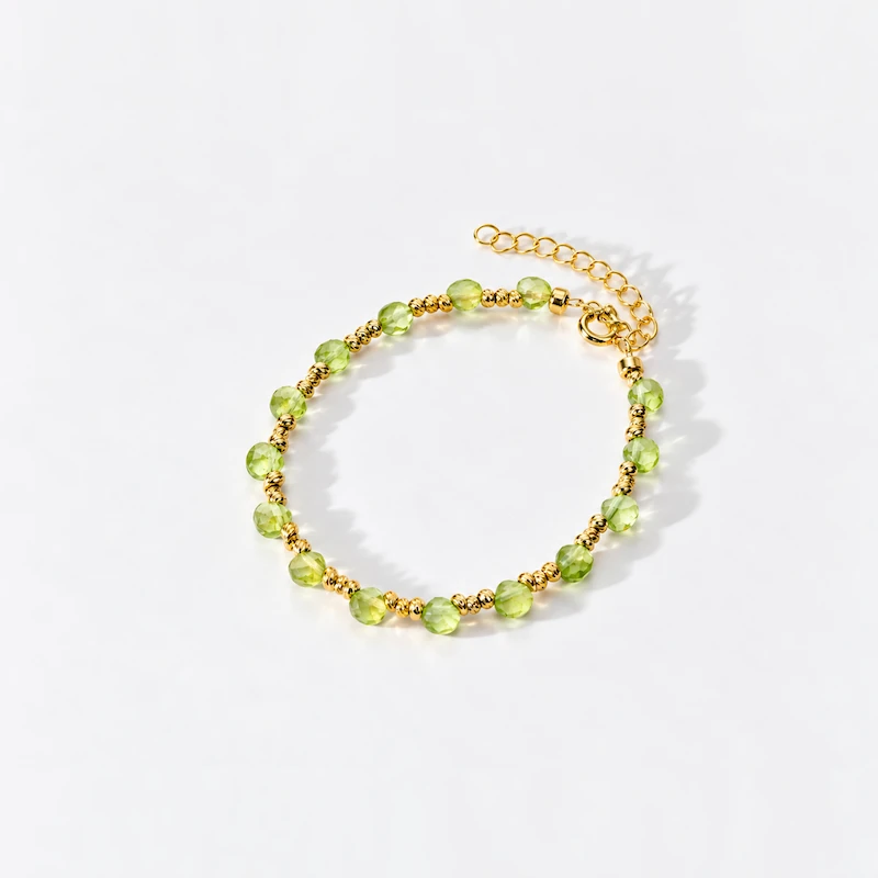 ONDA LENTA peridot bracelet featuring faceted light green peridot beads, gold-tone accent beads and an adjustable extension chain.