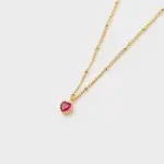 Perspective view showing textured gold bead accents and a faceted red heart pendant necklace in 18K gold plated sterling silver.