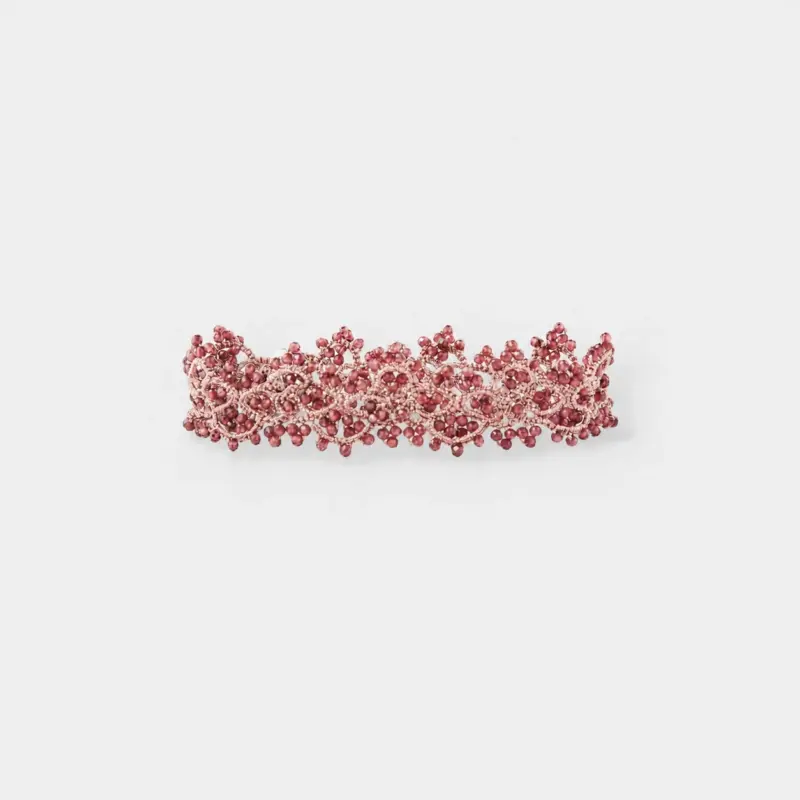 Side view showing the intricate openwork lace pattern woven with red garnet beads onto a flexible palladium plated metal frame.