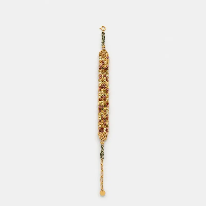 Horizontal flat lay view of vineyard woven gold bracelet showcasing detailed gemstone rows of green peridot and red garnet beads