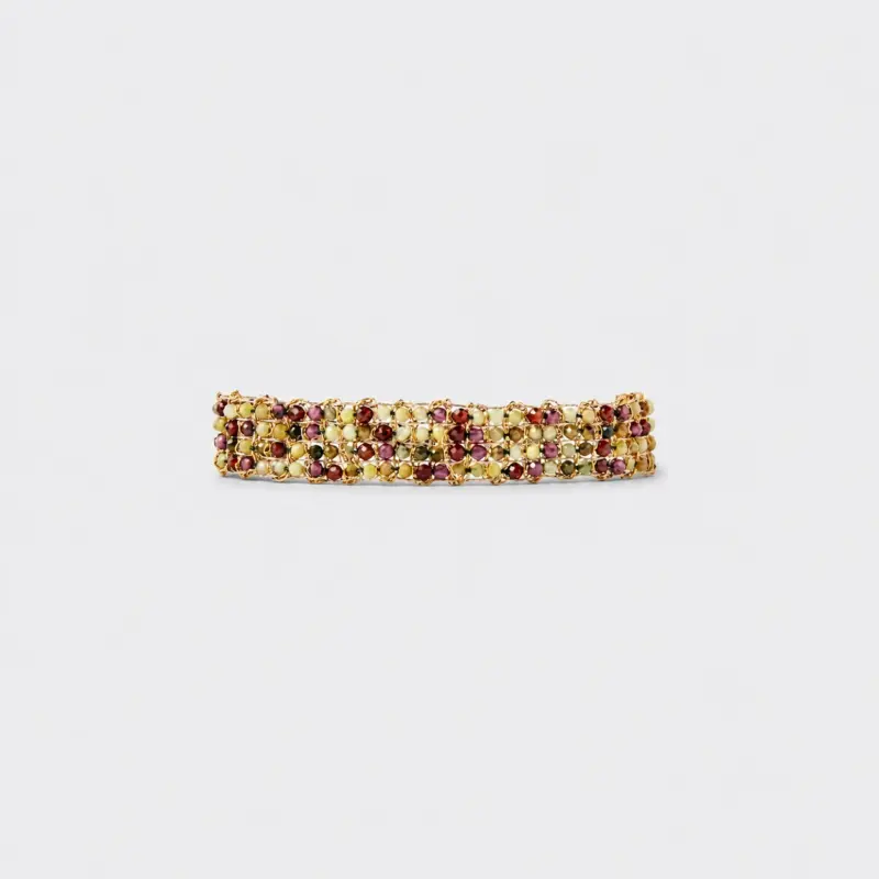Horizontal flat lay view of vineyard woven gold bracelet showcasing detailed gemstone rows of green peridot and red garnet beads