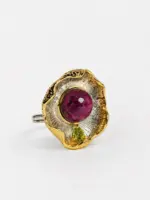 Side perspective of the pendant showcasing the textured radiating metalwork and the vibrant contrast between the ruby center and peridot accent