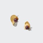 Close-up angled view showing the brushed gold surface and silver-toned textured detail of the sculptural stud earrings with secure backs, handcrafted in 18k gold plated sterling silver with vibrant ruby cabochons.