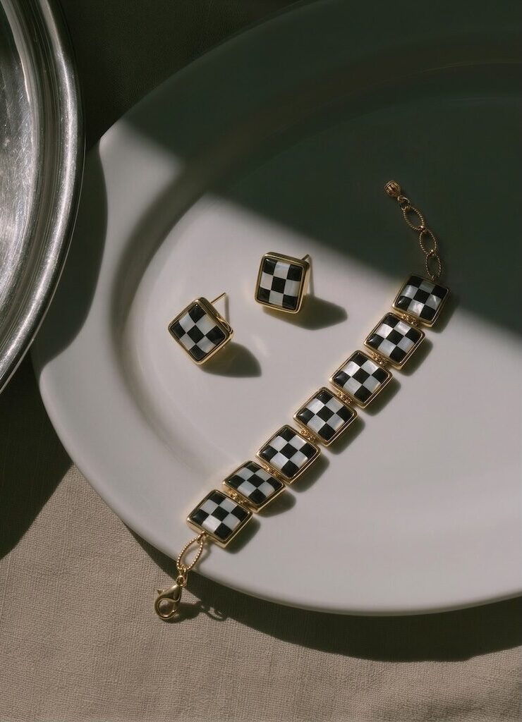 ONDA LENTA luxury 18K gold-plated jewelry set showcasing a square-link checkerboard pattern bracelet and matching stud earrings, elegantly arranged on a white ceramic plate under dramatic cinematic shadows.
