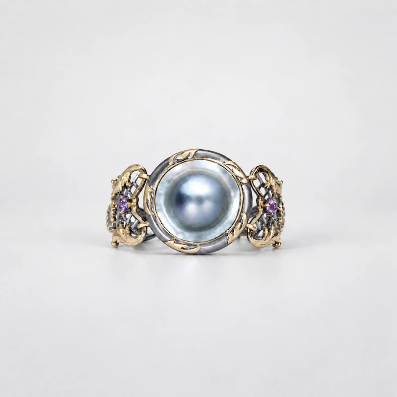 ONDA LENTA baroque pearl cuff bracelet featuring a large oval pearl centerpiece, two-tone gold and silver openwork design, and gemstone details.