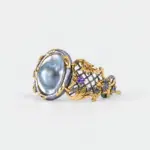 Side view of an ONDA LENTA statement cuff bracelet with a large baroque pearl, ornate openwork metal design, and vintage-inspired gemstone accents.